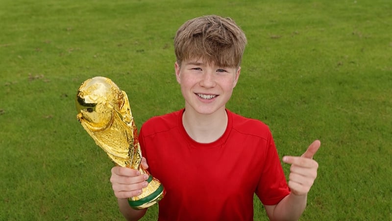Leo holding a football trophy on the pitch
